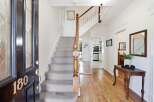 Step into this charming entryway featuring a grand staircase with plush carpeting and a classic wooden banister.