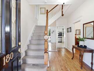 Step into this charming entryway featuring a grand staircase with plush carpeting and a classic wooden banister.