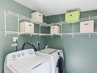 This laundry room features a corner shelving unit with storage bins, perfect for organizing detergents and supplies.