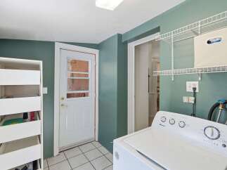 This laundry room features a convenient top-load Amana washing machine, perfect for handling all your laundry needs.