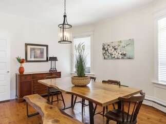 This dining room features a stunning live-edge dining table paired with rustic wooden chairs and a matching bench, creating a warm and inviting atmosphere.