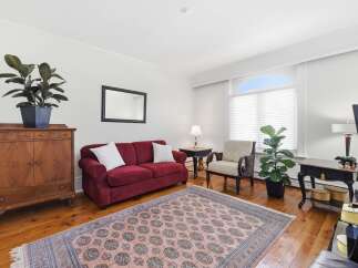 Step into this inviting living room, featuring a plush burgundy sofa and a charming wooden accent cabinet.