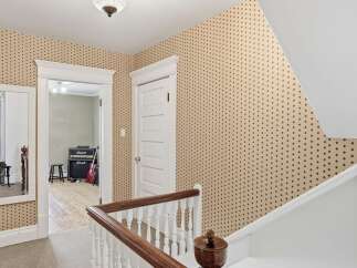 This charming hallway features a unique patterned wallpaper that adds character and warmth to the space.