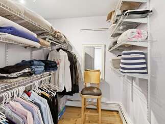 Discover ample storage in this well-organized walk-in closet, featuring extensive shelving for folded clothes and hanging garments.