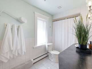 This bright and airy bathroom features a clean white tiled shower and walls, complemented by a light blue accent wall.