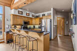 This spacious kitchen features warm wood cabinetry, a sleek black countertop, and a convenient breakfast bar with seating.