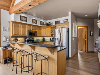 This spacious kitchen features warm wood cabinetry, a sleek black countertop, and a convenient breakfast bar with seating.
