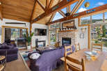 Experience mountain living in this charming living room featuring a stunning stone fireplace and vaulted wood-beamed ceilings.
