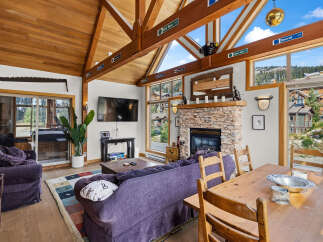 Experience mountain living in this charming living room featuring a stunning stone fireplace and vaulted wood-beamed ceilings.