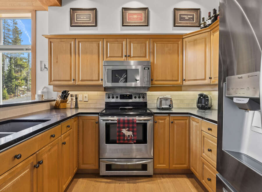 This charming kitchen boasts beautiful light wood cabinetry, complemented by sleek black countertops and a matching sink.