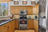 This charming kitchen boasts beautiful light wood cabinetry, complemented by sleek black countertops and a matching sink.