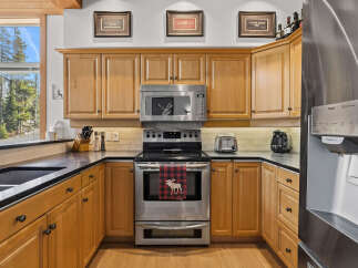 This charming kitchen boasts beautiful light wood cabinetry, complemented by sleek black countertops and a matching sink.