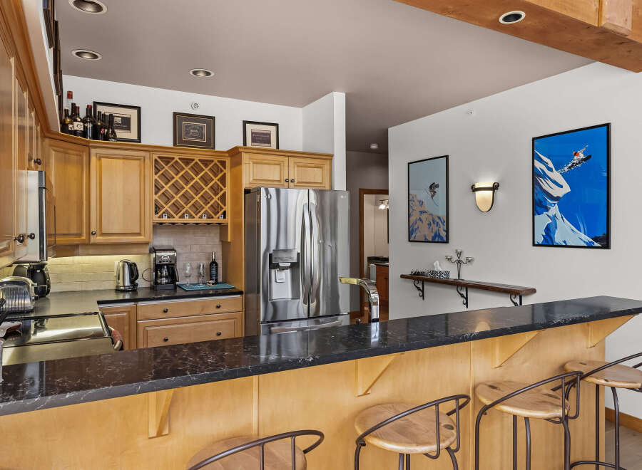 This spacious kitchen features elegant wood cabinetry, a wine rack, and a sleek granite countertop bar perfect for entertaining.