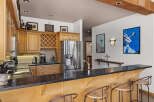 This spacious kitchen features elegant wood cabinetry, a wine rack, and a sleek granite countertop bar perfect for entertaining.