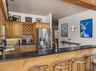 This spacious kitchen features elegant wood cabinetry, a wine rack, and a sleek granite countertop bar perfect for entertaining.