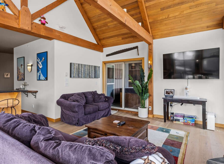 Experience rustic charm and modern comfort in this inviting living space, featuring exposed wooden beams and a vaulted ceiling that create an airy, open atmosphere.