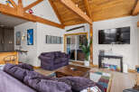 Experience rustic charm and modern comfort in this inviting living space, featuring exposed wooden beams and a vaulted ceiling that create an airy, open atmosphere.