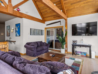 Experience rustic charm and modern comfort in this inviting living space, featuring exposed wooden beams and a vaulted ceiling that create an airy, open atmosphere.