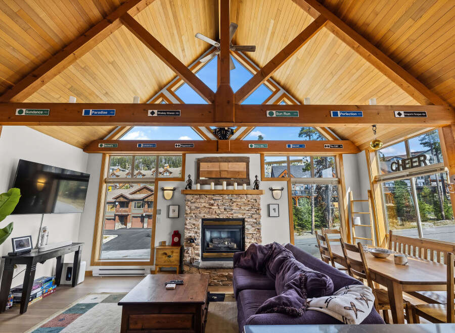 Experience the ultimate mountain retreat in this stunning living room, featuring a soaring vaulted wood-paneled ceiling and a cozy stone fireplace.