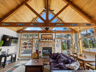 Experience the ultimate mountain retreat in this stunning living room, featuring a soaring vaulted wood-paneled ceiling and a cozy stone fireplace.