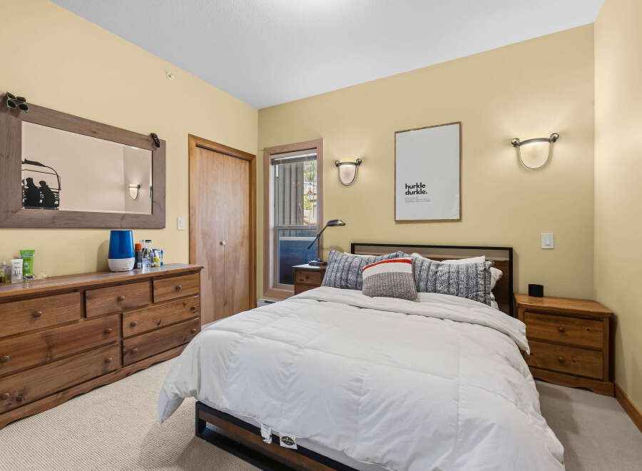 This cozy bedroom features a comfortable queen-size bed with plush white bedding, perfect for a restful night's sleep.