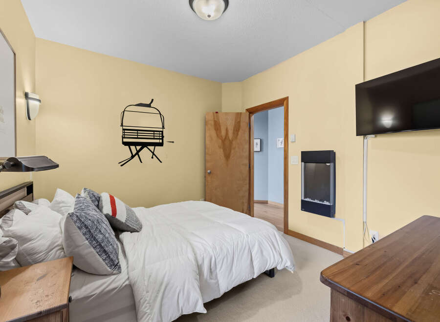 This cozy bedroom features a comfortable queen-size bed adorned with plush pillows and a crisp white duvet.