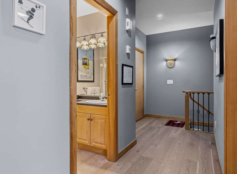 Discover this charming hallway featuring a stylish bathroom vanity with ample storage and a large mirror.