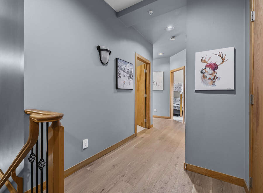 This hallway features a modern aesthetic with light wood flooring and a calming blue-grey wall color.