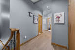 This hallway features a modern aesthetic with light wood flooring and a calming blue-grey wall color.