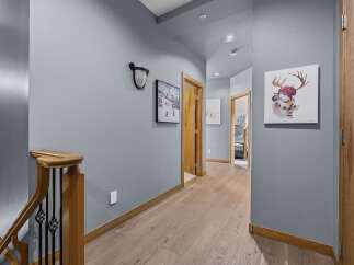 This hallway features a modern aesthetic with light wood flooring and a calming blue-grey wall color.
