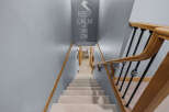 Descend into comfort and style with this carpeted staircase, featuring a smooth wooden handrail and elegant black balusters.