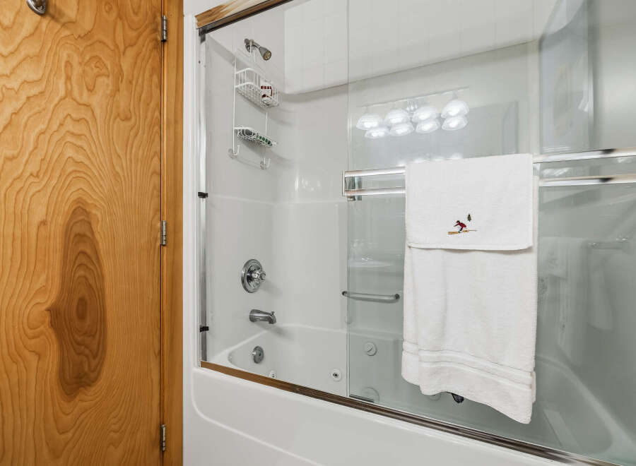 Step into this inviting bathroom featuring a pristine white bathtub and shower combination, enclosed by a sleek glass door.