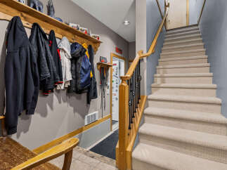 This entryway features a convenient coat rack with multiple jackets and hoodies, perfect for a busy household.
