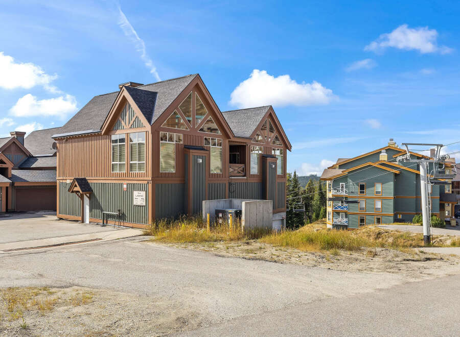 Experience mountain living in this charming property featuring a distinctive A-frame design with warm wood siding and large windows.