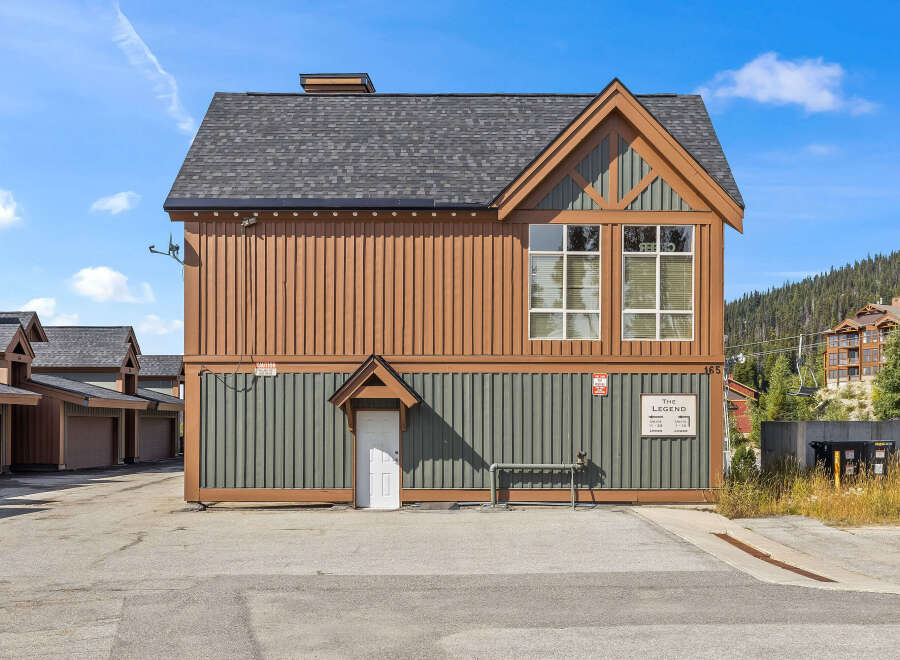 Discover this charming property featuring a unique architectural design with warm brown and green siding, complemented by a dark asphalt shingle roof.