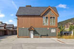 Discover this charming property featuring a unique architectural design with warm brown and green siding, complemented by a dark asphalt shingle roof.