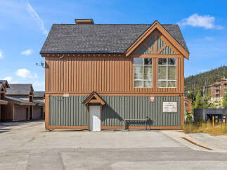 Discover this charming property featuring a unique architectural design with warm brown and green siding, complemented by a dark asphalt shingle roof.