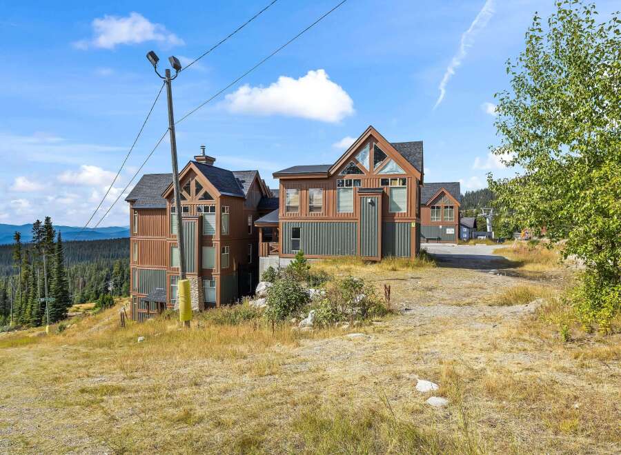 Experience mountain living in this stunning property featuring modern architecture with warm wood and dark green siding.
