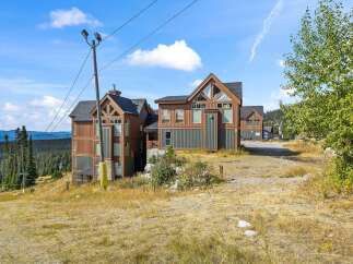 Experience mountain living in this stunning property featuring modern architecture with warm wood and dark green siding.