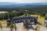Discover this stunning mountain property featuring a complex of modern chalets with dark roofs and rich wood exteriors, nestled amidst a dense pine forest.