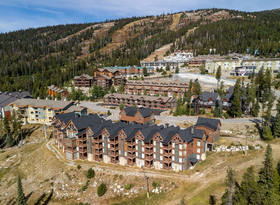 Discover this stunning mountain resort property, featuring a collection of modern lodges nestled against a backdrop of lush pine forests and ski slopes.
