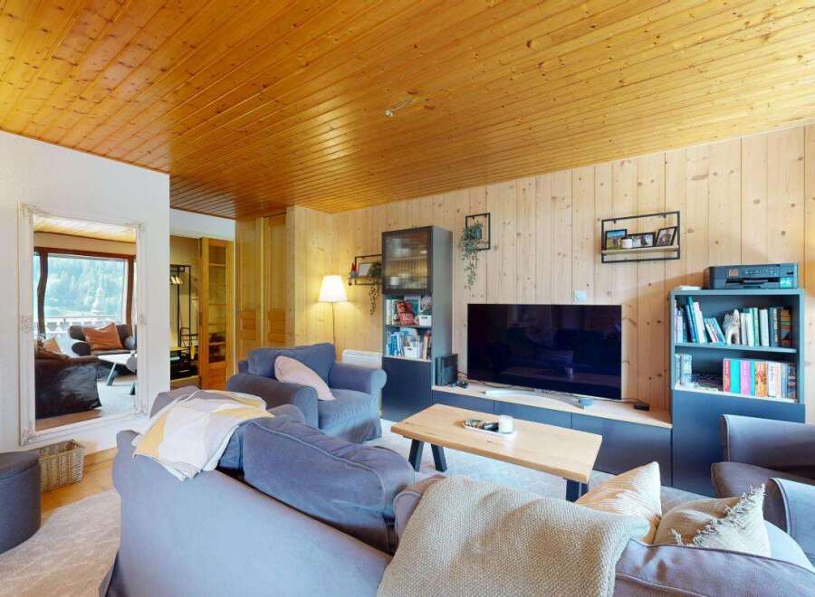 Experience cozy living in this charming mountain retreat, featuring a warm wooden ceiling and walls that create a rustic ambiance.