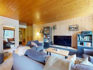Experience cozy living in this charming mountain retreat, featuring a warm wooden ceiling and walls that create a rustic ambiance.