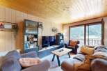 Experience cozy living in this charming mountain retreat, featuring a warm wood-paneled interior and a spacious living area perfect for relaxation.