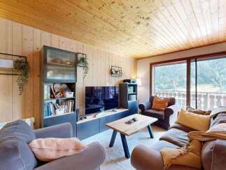 Experience cozy living in this charming mountain retreat, featuring a warm wood-paneled interior and a spacious living area perfect for relaxation.