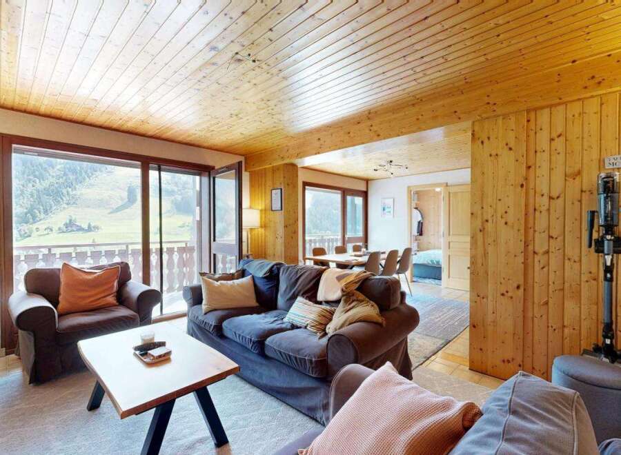Experience breathtaking mountain views from this charming living room, featuring a cozy sofa and armchair perfect for relaxing after a day of adventure.