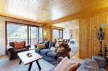 Experience breathtaking mountain views from this charming living room, featuring a cozy sofa and armchair perfect for relaxing after a day of adventure.