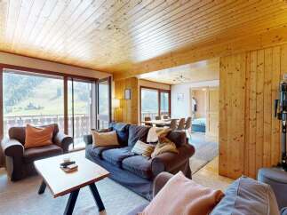 Experience breathtaking mountain views from this charming living room, featuring a cozy sofa and armchair perfect for relaxing after a day of adventure.