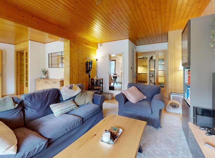 Experience cozy living in this charming mountain retreat, featuring a warm wooden ceiling and walls that create an inviting atmosphere.