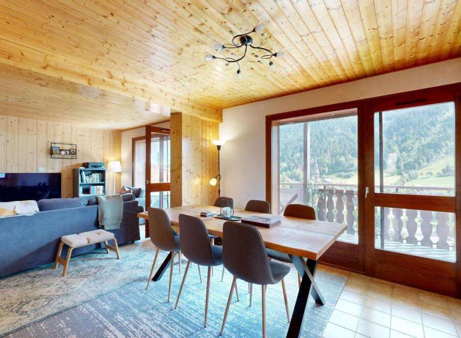 Experience breathtaking mountain views from this charming dining area, featuring a rustic wooden table and comfortable seating.